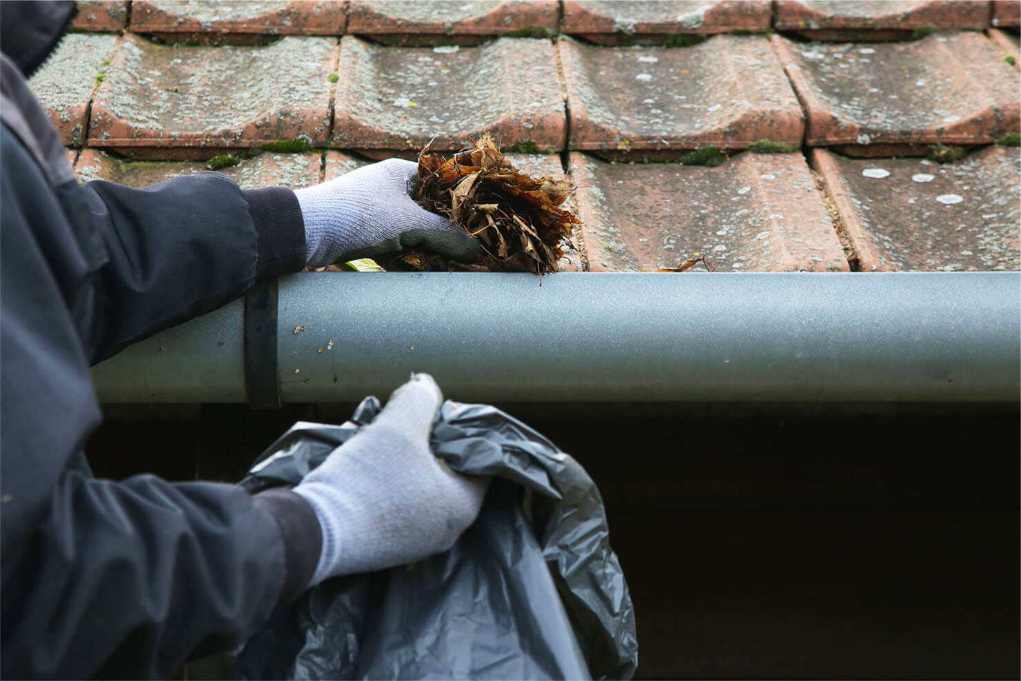 Inspector providing roofing maintenance in the Dayton area by cleaning out clogged gutters.